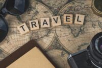 Vintage map with travel essentials like camera and sunglasses arranged in a flat lay, perfect for adventure themes.